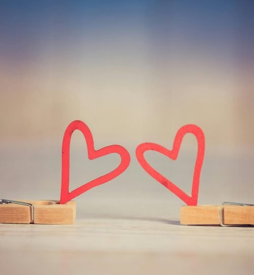 legal Two wooden clothespins with red heart shapes, symbolizing love and romance, on a blurred background.